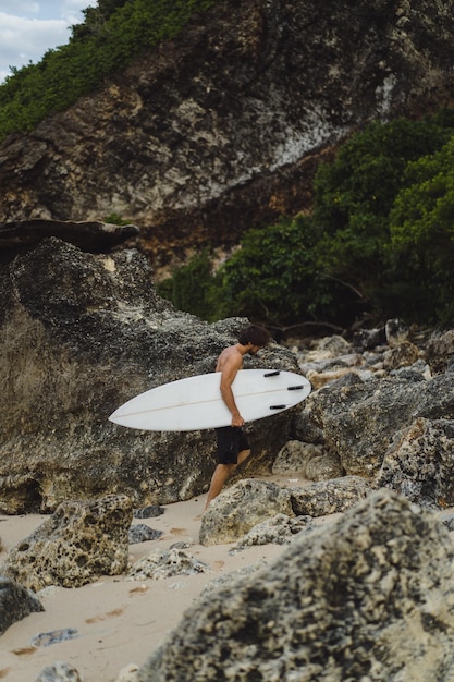 Foto grátis conceito de oceano tropical surfista surfista esporte ao ar livre. jovem bonito com uma prancha de surf no oceano.