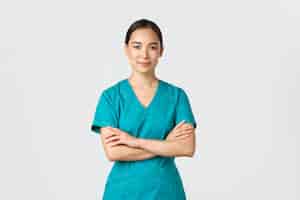 Foto grátis conceito de pandemia de trabalhadores de saúde covid19 enfermeira asiática sorridente confiante em jaleco em pé peito de braços cruzados confiante médico profissional pronto para cirurgia em pé fundo branco