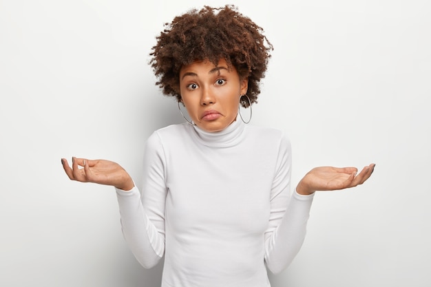 Conceito de percepção de pessoas, atitude e vida. mulher desavisada sem noção com cabelo encaracolado, espalhando as palmas das mãos na dúvida