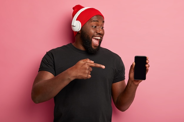 Conceito de pessoas, tecnologia, estilo de vida e publicidade. Homem feliz de pele escura mostra a tela em branco do dispositivo smartphone