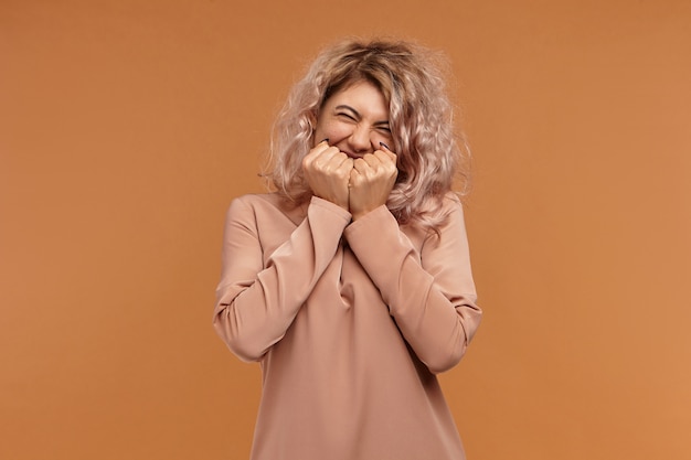 Conceito de positividade, alegria e felicidade. foto de garota hippie alegre e cheia de alegria em roupas elegantes, sorrindo alegremente, segurando a boca de mãos dadas