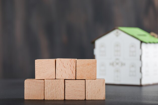 Conceito de propriedade com cubos de madeira, modelo de casa e cinza.