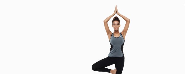 Conceito de saúde e fitness Linda senhora africana americana em roupas de fitness fazendo ioga e meditação Isolado em fundo branco