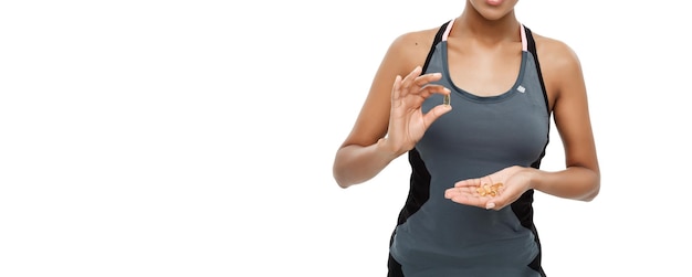 Foto grátis conceito de saúde e fitness retrato aproximado de uma bela afro-americana tomando uma pílula de óleo de fígado de bacalhau isolado no fundo branco do estúdio