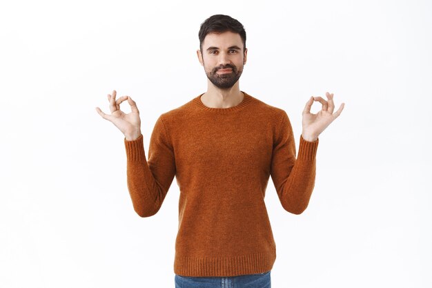 Conceito de saúde mental, pessoas e quarentena. Retrato de um homem barbudo bonito e paciente se distanciando durante a pandemia de covid 19 em casa, tentando ficar calmo e relaxado, meditando, sentindo-se bem