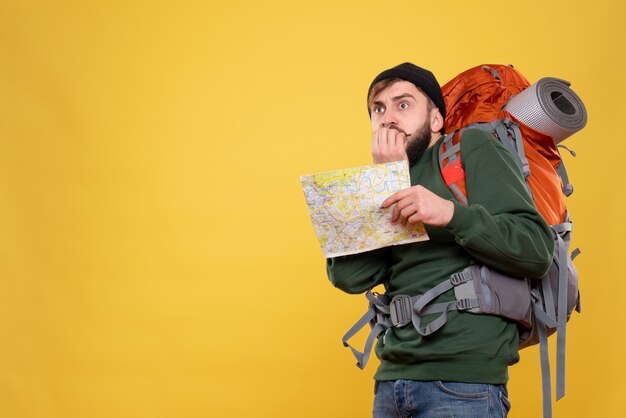 Conceito de viagens com jovem assustado com packpack e mostrando o mapa em amarelo