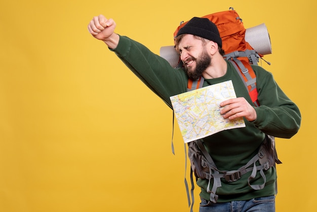 Conceito de viagens com jovem orgulhoso com packpack e segurando mapa em amarelo