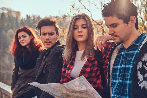 Conceito de viagens, turismo, caminhada e pessoas. Foto de close-up de jovens amigos olhando para o mapa e planejando viagem na floresta de outono.