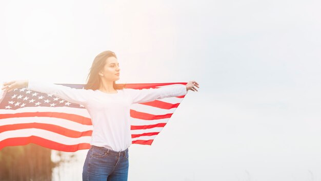 Conceito do dia da independência com a mulher segurando a bandeira no fundo do céu