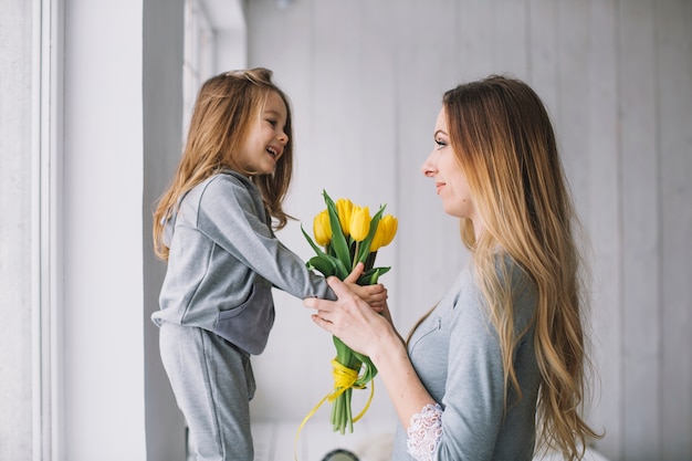 Conceito do dia das mães com mãe e filha segurando flores amarelas