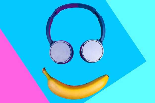 Conceito plano de pop art de banana e fones de ouvido em um fundo de cores vivas, formando um rosto sorridente. Estilo simples e cores