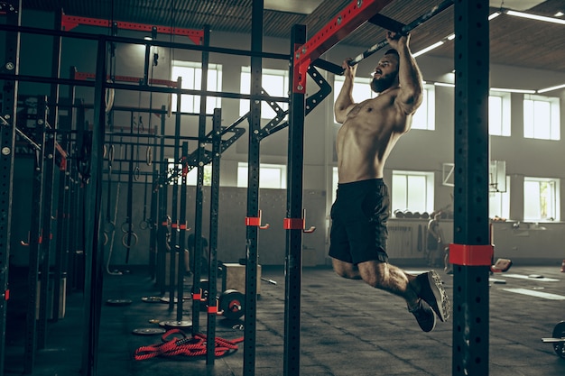 Foto grátis conceito: poder, força, estilo de vida saudável, esporte. poderoso homem musculoso atraente no ginásio