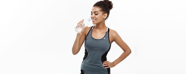 Foto grátis conceito saudável e fitness linda garota afro-americana em roupas esportivas bebendo água por plas