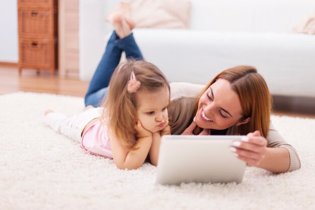 Concentre a menina com a mãe usando o tablet digital em casa