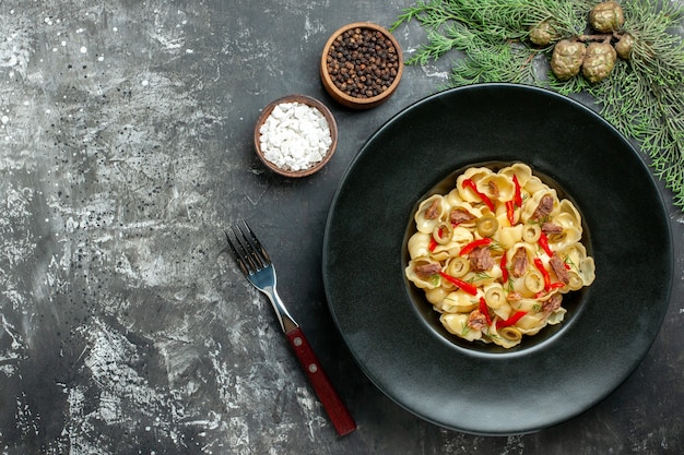 Foto grátis conchiglie deliciosa com legumes e verduras em um prato e uma faca e especiarias diferentes em fundo cinza