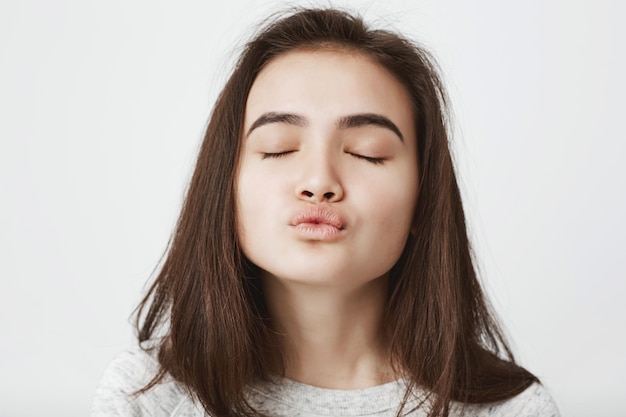 Foto grátis concurso atraente mulher europeia à espera de beijo com os lábios dobrados e os olhos fechados.