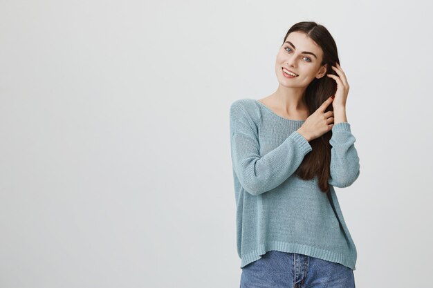 Concurso atraente mulher tocando o cabelo suavemente, sorrindo