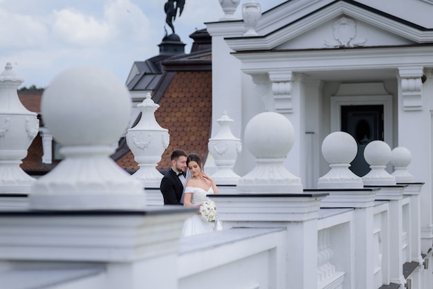 Concurso casal apaixonado está de pé ao ar livre perto do edifício no dia do casamento