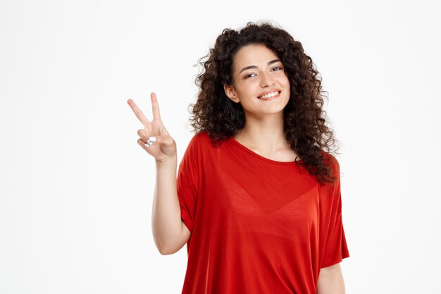 Concurso garota encaracolada, sorrindo e mostrando o gesto de paz