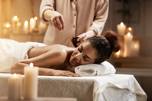 Concurso mulher africana relaxante desfrutando saudável spa massagem com óleo.