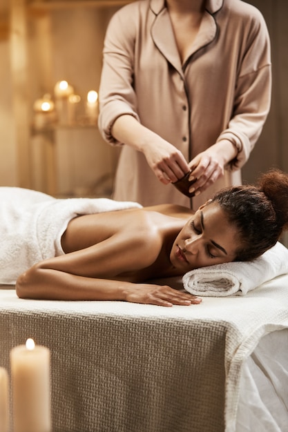 Concurso mulher africana relaxante desfrutando saudável spa massagem com óleo.