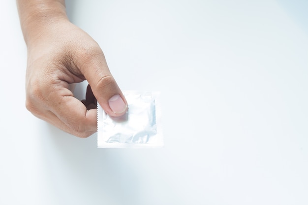 Condom na mão masculina no fundo branco