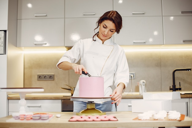 Foto grátis confeiteiro de uniforme decora o bolo