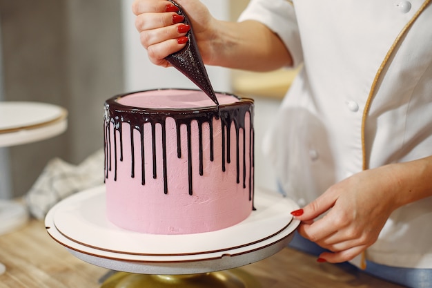 Foto grátis confeiteiro de uniforme decora o bolo