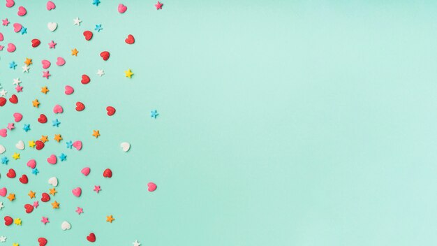 Confetes de estrelas e corações em um fundo turquesa com espaço de cópia