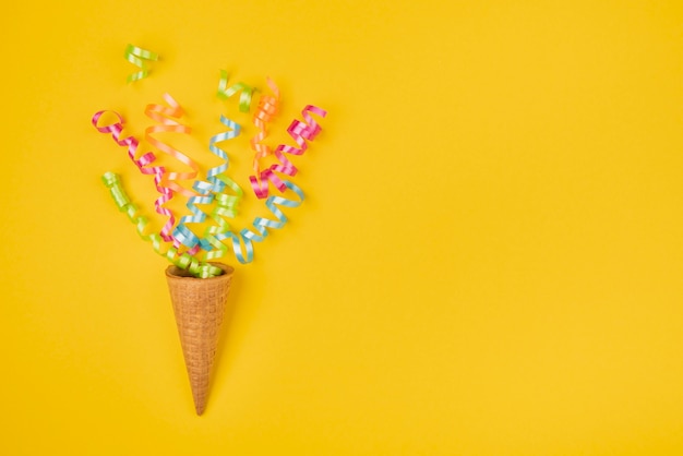 Confetes em casquinha de sorvete com cópia espaço em fundo amarelo