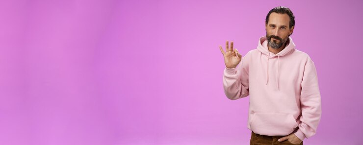 Foto grátis confiante, bonito, sortudo, velho, macho, barbudo, cabelo cinzento, com um elegante capuz rosa, com um bolso na mão.