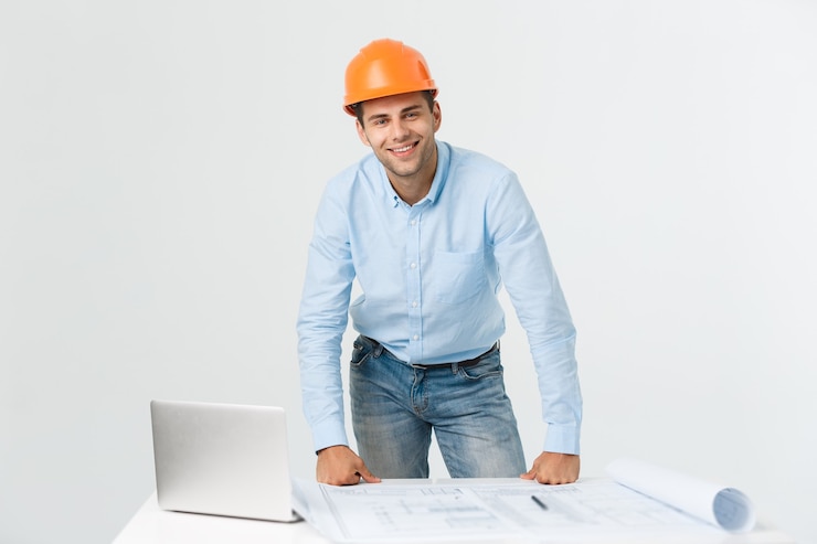 Foto grátis confiante em seu novo projeto. jovem engenheiro e arquiteto trabalhando no laptop e olhando para a câmera com um sorriso em seu escritório.