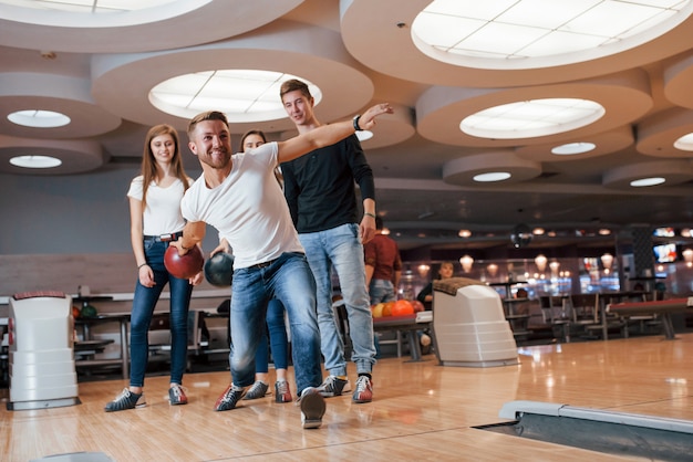 Confiante em sua própria força. jovens amigos alegres se divertem no clube de boliche nos fins de semana