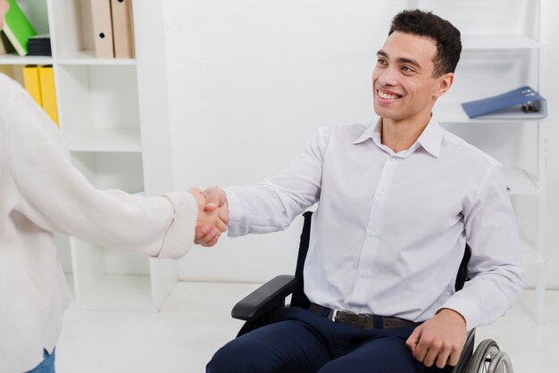 Confiante, homem negócios, sentando, ligado, cadeira rodas, apertar mão, com, dela, femininas, colega