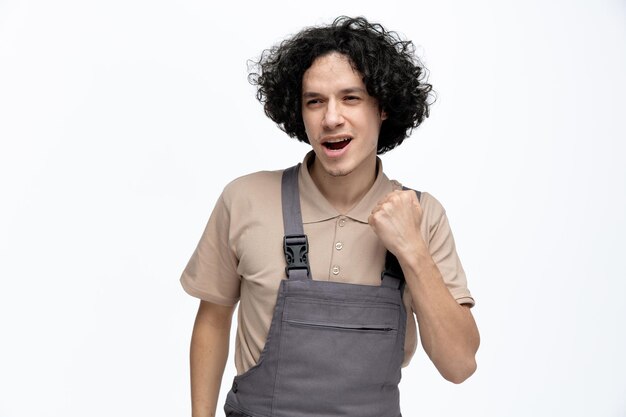 Foto grátis confiante jovem trabalhador da construção civil vestindo uniforme olhando para o lado fazendo sim gesto isolado no fundo branco