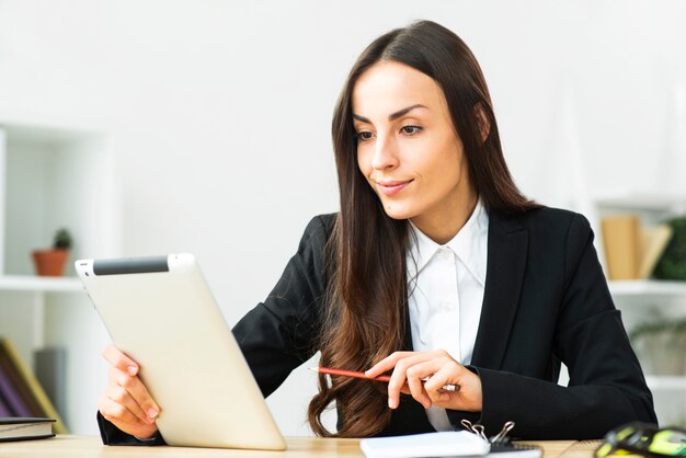 Confiante sorridente jovem empresária olhando tablet digital no escritório