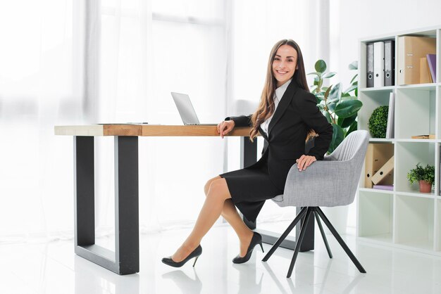 Confiante, sorrindo, jovem, executiva, sentando escrivaninha, em, dela, modernos, escritório