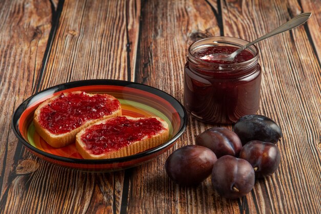 Confiture de ameixas em potes de vidro com tostas de pão.