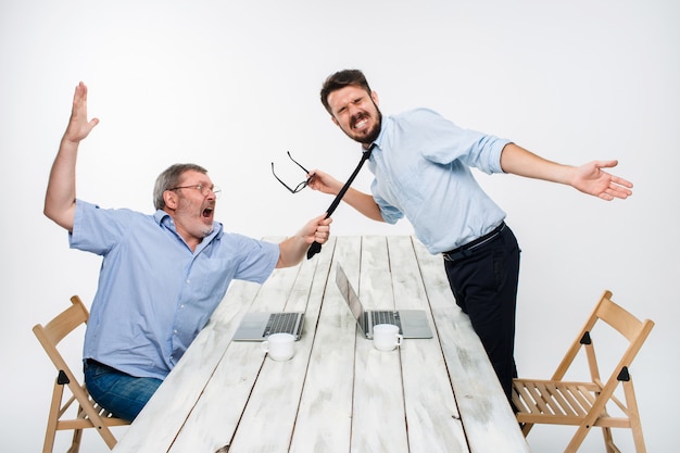 Foto grátis conflito de negócios. os dois homens expressando negatividade enquanto um homem agarra a gravata de seu oponente