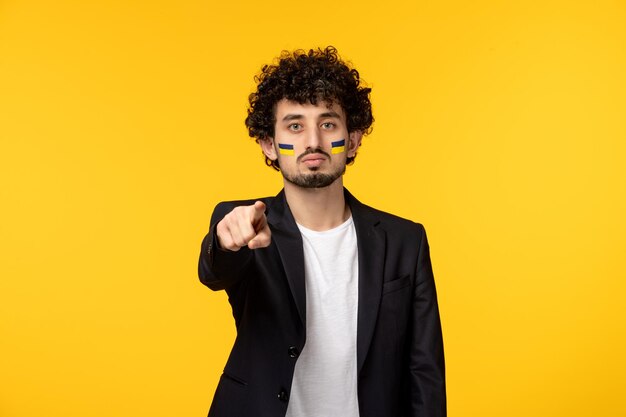 Conflito russo da Ucrânia jovem em blazer pintado bandeira ucraniana no rosto apontando com o dedo