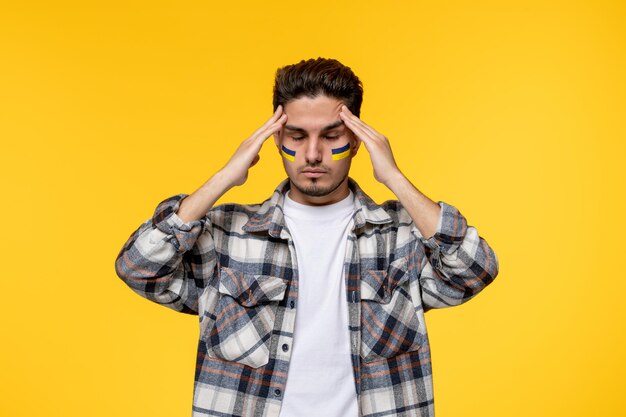 Conflito russo na Ucrânia, um jovem bonito e bonito com bandeiras nas bochechas segurando templos cansados