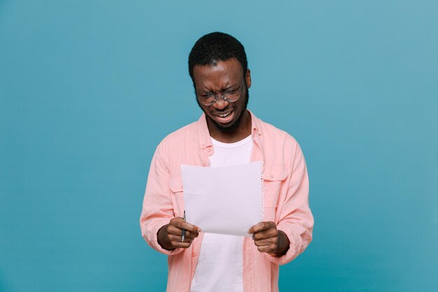 Confuso segurando papel jovem afro-americano isolado em fundo azul