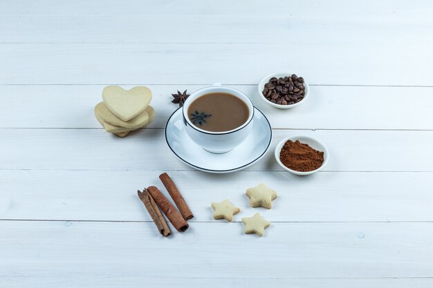 Conjunto de biscoitos, especiarias, grãos de café, café moído e café em uma xícara em um fundo de madeira. vista de alto ângulo.