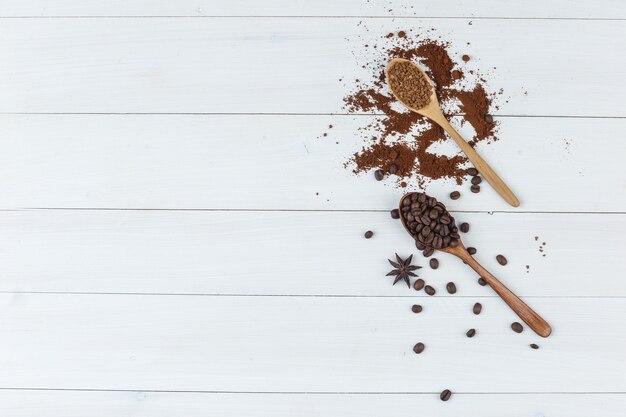 Conjunto de café moído e grãos de café em uma colher de pau em um fundo de madeira. colocação plana.