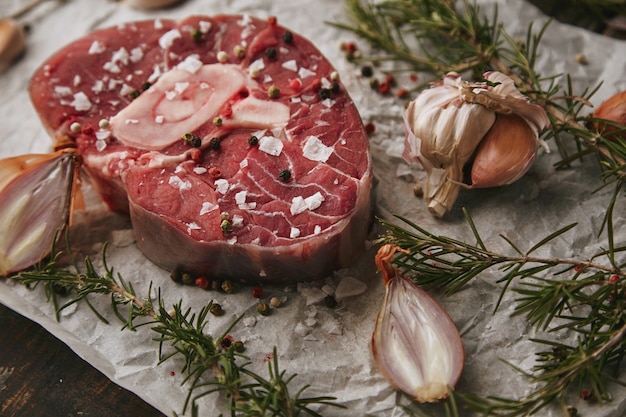 Conjunto de comida, cebola, romero, bife de carne crua, sal, pimenta, alho, azeite, garfo, closeup