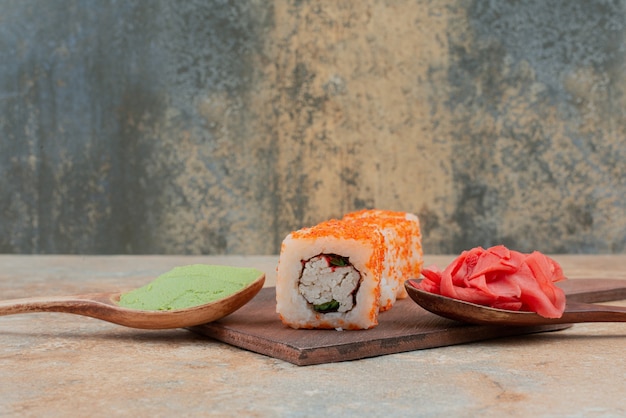 Conjunto de delicioso sushi roll com colher e molho de soja no mármore