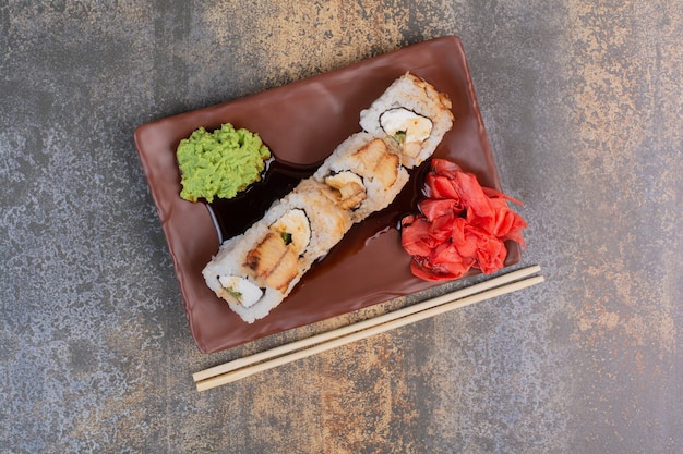 Conjunto de deliciosos sushis com pauzinhos e gengibre em espaço de mármore