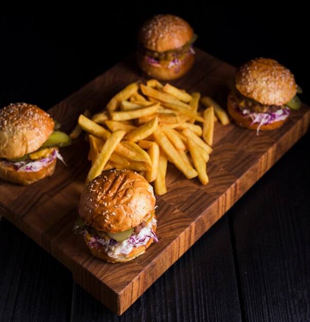 Conjunto de hambúrgueres clássicos com batatas fritas em uma placa de madeira