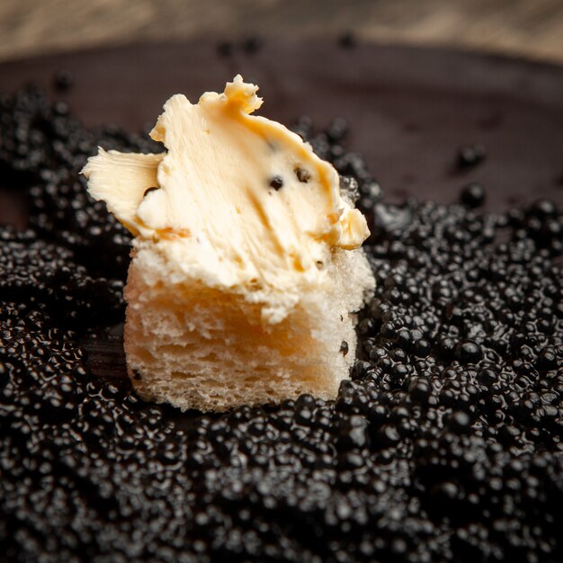 Conjunto de pão com manteiga e caviar preto sobre um fundo escuro. vista de alto ângulo.