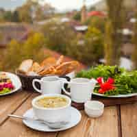 Foto grátis conjunto de pão, verduras, salada e refeição deliciosa sopa em uma tigela com uma vila no fundo. vista de alto ângulo.